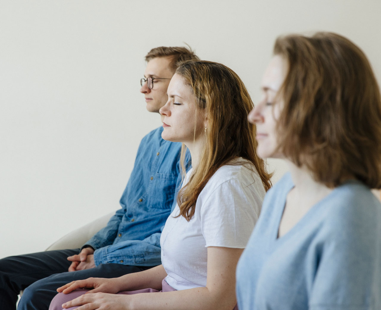 люди практикуют Трансцендентальную Медитацию сидя на диване с закрытыми глазами