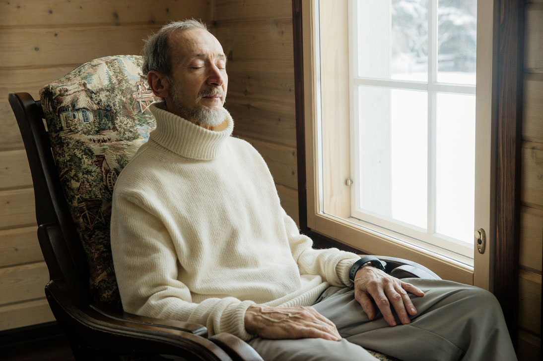 мужчина практикует ТМ сидя в кресле у окна